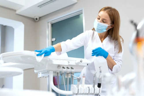 dental assistant wearing gloves and mask while sterilizing dental equipment